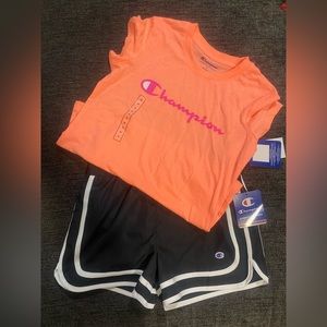 Orange top with pink Champion writing. Black champion shorts